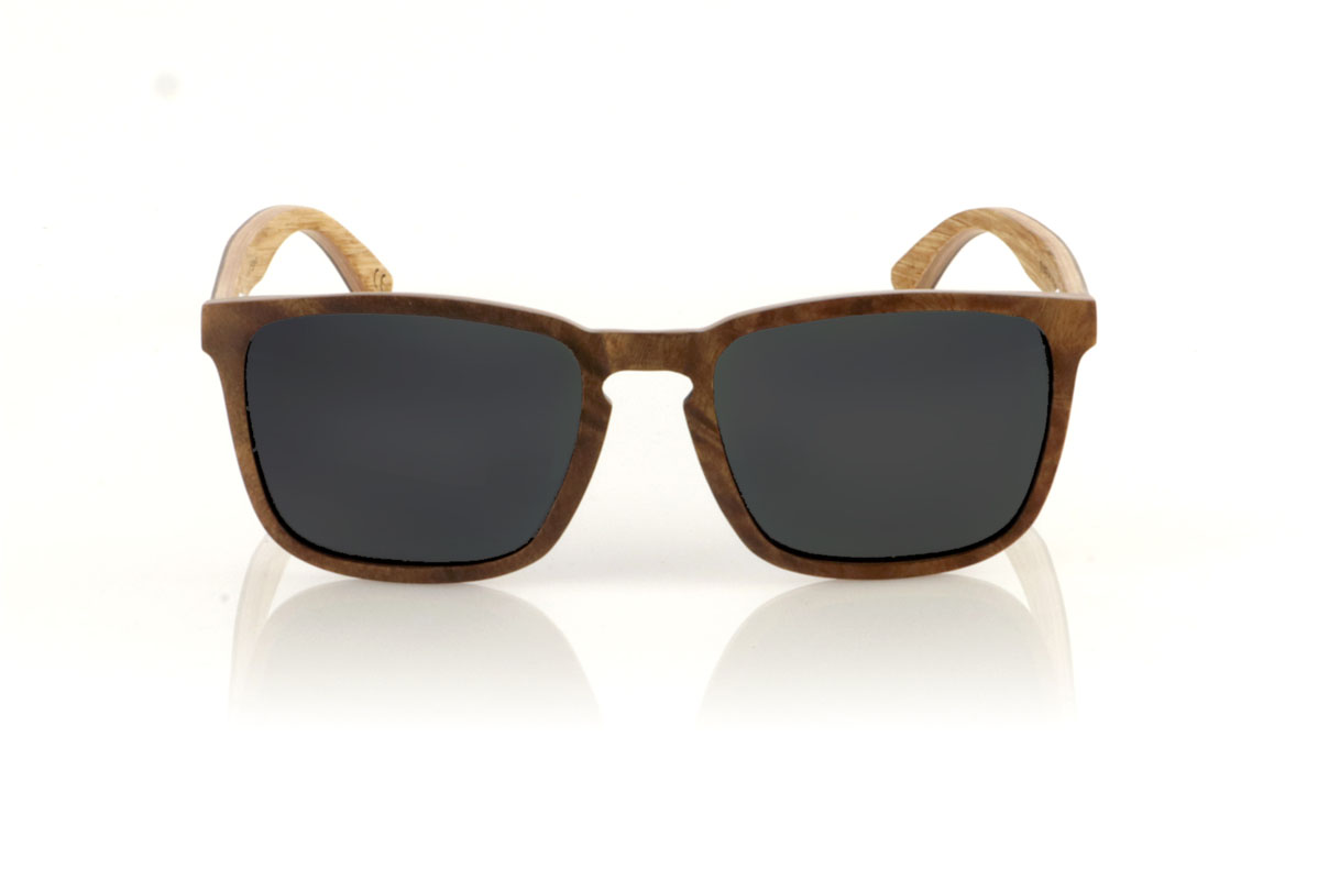 Wood eyewear of Burr OLIVER. OLIVER wooden sunglasses, medium in size and with a square shape with rounded and soft lines, are the perfect balance between design and nature. Made with a careful lamination of olive wood on the outside and interspersed with layers of beech wood, they stand out for the warm color and unique grain that olive wood offers. This combination not only provides exceptional resistance, but also makes each pair a unique piece. With a measurement of 145x47 and a caliber of 53, the OLIVER adapts wonderfully, offering comfort and unmistakable style to those who wear them. Ideal for those looking to stand out with an accessory that speaks of elegance and commitment to the environment. for Wholesale & Retail | Root Sunglasses® 